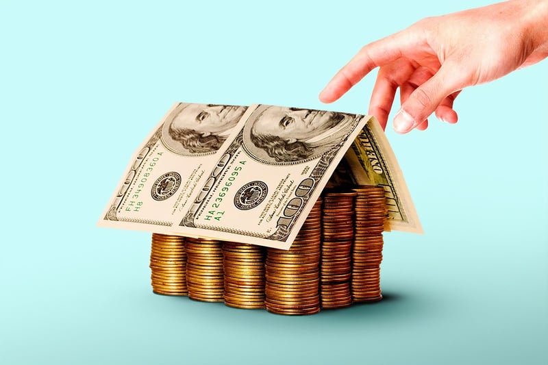 Hand moving over a house made of dollars and coins