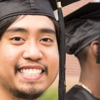 A smiling Asian male student at a graduation event