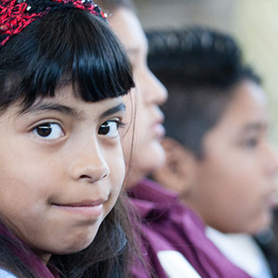A young girl in a classroom with other classmates