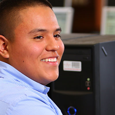 A smiling male employee at work in front of a computer