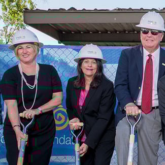 A man and two women at a first-shovel ground-breaking construction event