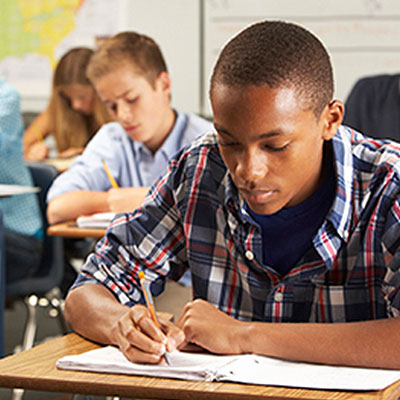 An African-American male student doing homework in class
