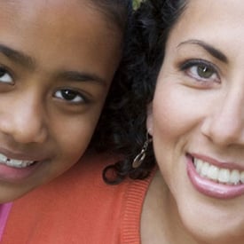 Mother and daughter, smiling, looking into the camera