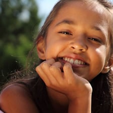 Young girl resting her chin on her hand smiling at the camera