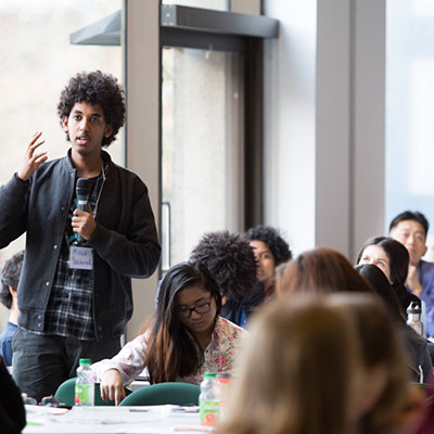 A speaker walking around a room full of listeners at an event