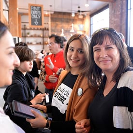 a group of people, smiling, mingling and conversing at an event