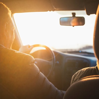 Driver inside a car driving into a sunset