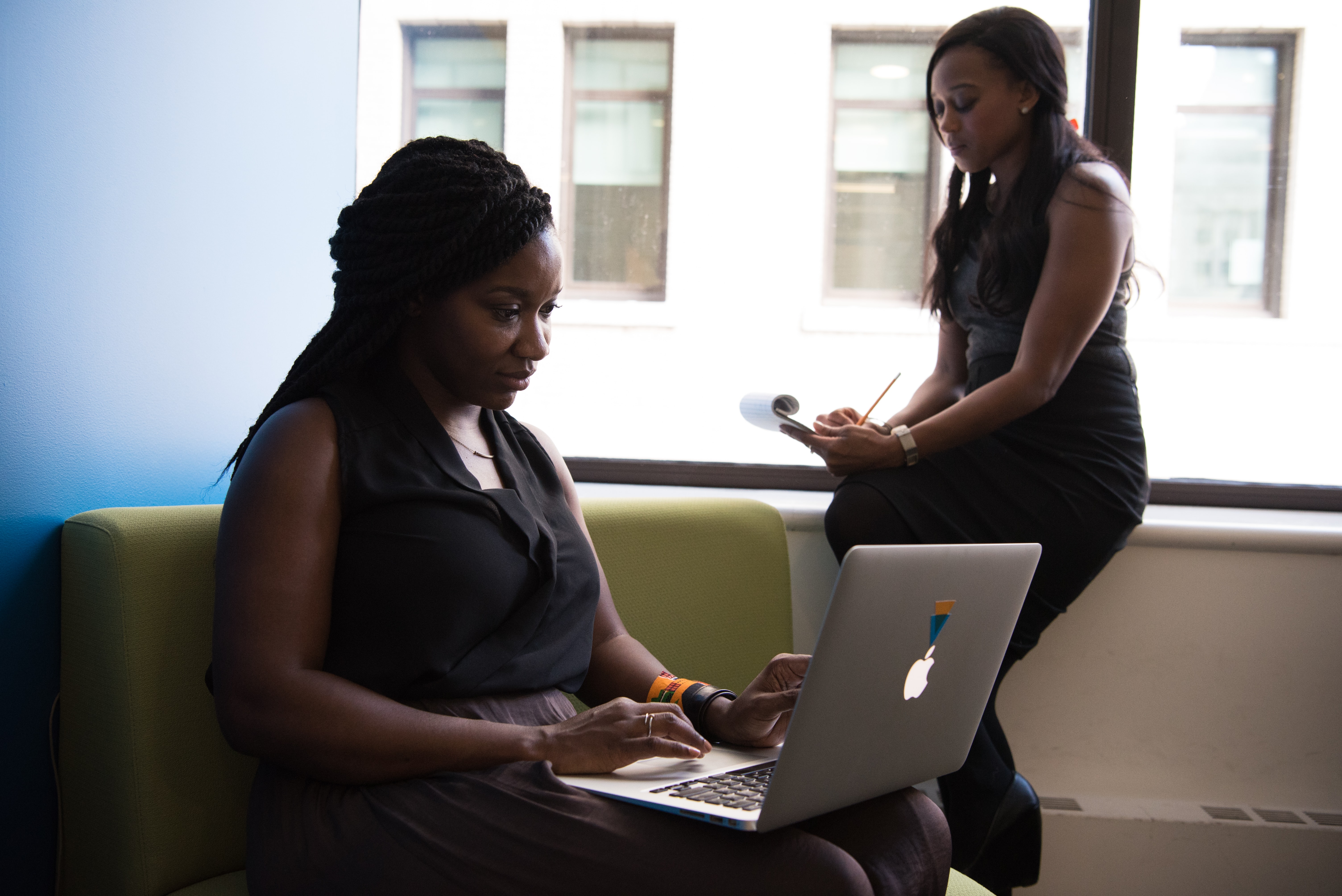 Women working on a computer and taking notes