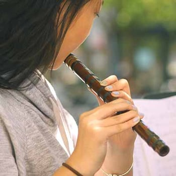 Young girl playing a wooden flute