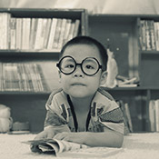 A photo of a little boy with round rimmed glasses at the library